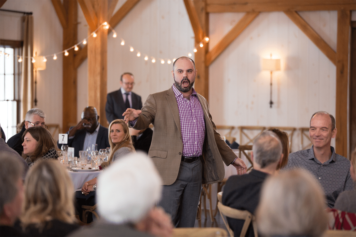 Man singing opera in between tables at a wine tasting event