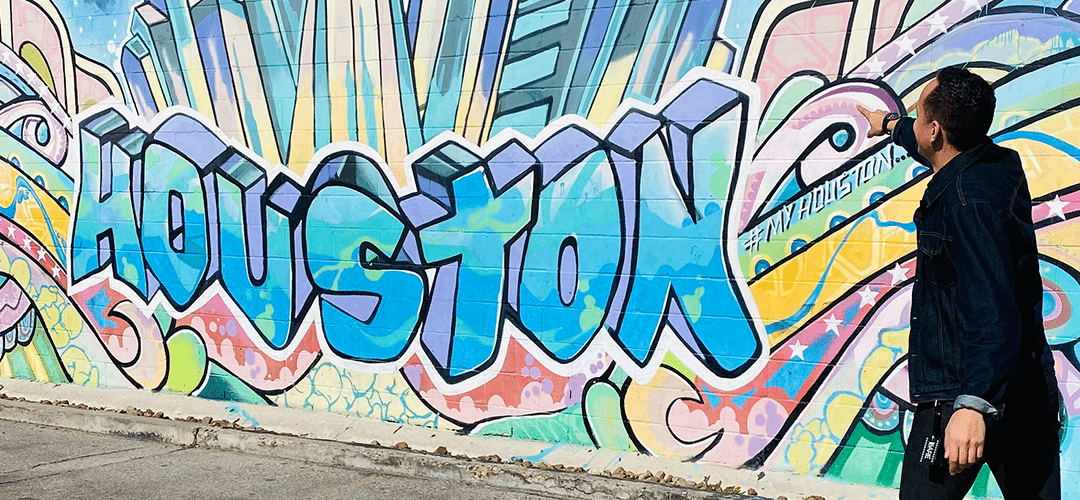 Julian Hernandez pointing at a graffiti wall that says "Houston"